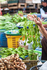 Asian woman vendor selling fresh Bitter Bean.
