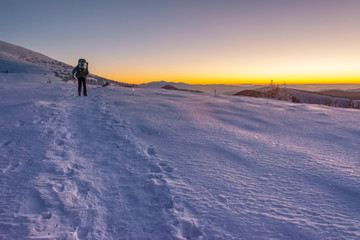 Traveling tourists on the snowy winter mountain ranges of the Ukrainian Carpathians with beautiful views of the evening peaks.