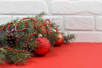 New Year's decoration. Red balls, Christmas tree, white wall, red background.