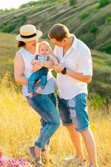 Happy family with little baby spending time together at sunset
