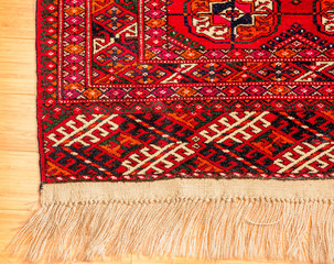 Beautiful hand woven oriental carpet isolated against wooden floor. 