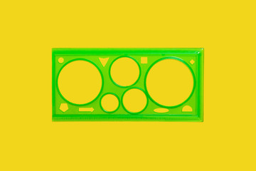 green plastic ruler with circles lying on a yellow background . concept of office supplies. free space for advertising text