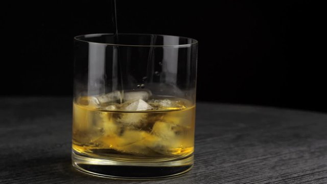 whiskey is poured into a glass with ice