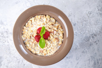 Healthy breakfast. Baked granola with milk and raspberries with mint in a plate. Tasty muesli, close-up