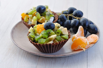 Dessert: Chocolate baskets with pieces of fruit (kiwi, banana, mandarin, grapes) inside.