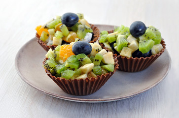 Dessert: Chocolate baskets with pieces of fruit (kiwi, banana, mandarin, grapes) inside.