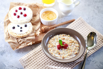 Baked granola with milk and raspberries in a plate, whole grain breads and freshly squeezed juice. A wholesome and dietary breakfast. Delicious muesli