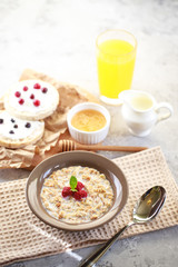 Baked granola with milk and raspberries in a plate, whole grain breads and freshly squeezed juice. A wholesome and dietary breakfast. Delicious muesli