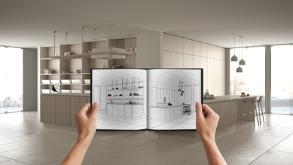 Hands holding notepad with creative kitchen design blueprint sketch or drawing. Real interior...