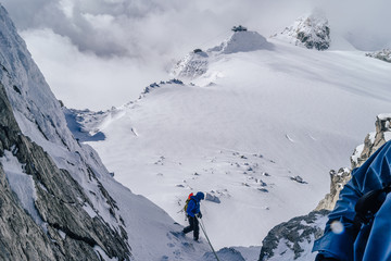 Alpinst rappeling down from a mountain. WInter alpine climbing on snow and rock. Abseiling on rope on a glacier, Mont Blanc Massif, France.