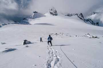 Climbers walking on a glacier using rope and ice axe. Alpinist in high alpine mountain landscape, walking in snow. Adventure outdoor activity.