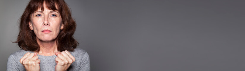 fighting middle aged woman hoping strong for success, grey banner