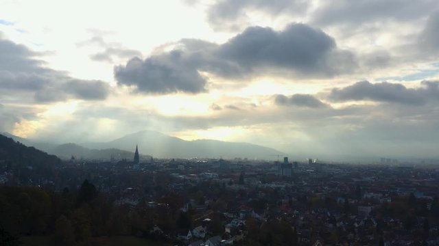Aerial view around the city Freiburg in Germany on a cloudy day, late afternoon in Autumn in the black forest. Slow ascend and tilt down beside the city.