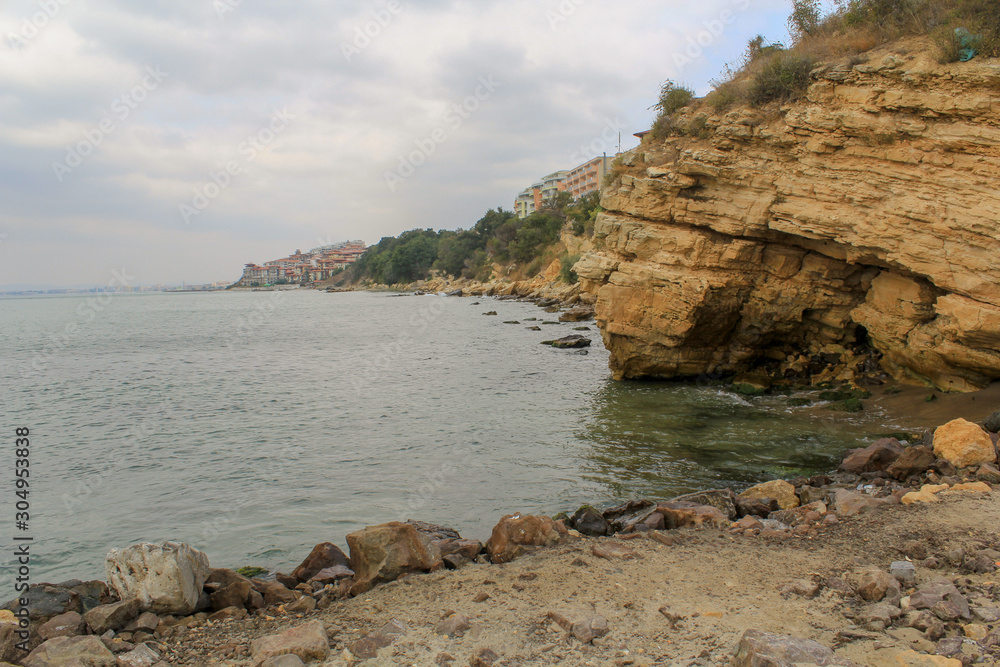 Wall mural View of the mountainous coast with sandy layered stones and houses standing on the edge