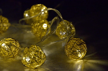 Christmas garland with elements in the form of balls with burning yellow lights lies on the surface, close-up, selective focus