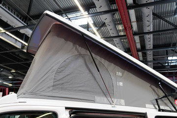 Camper van with tent on roof on dealership showroom