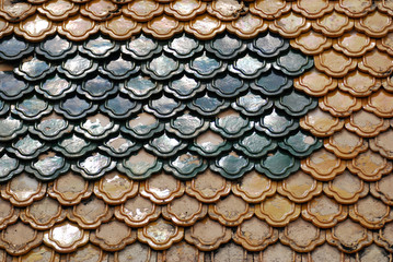 Abstract scene of yellow and green  earthenware tiles or calls tiles consists of fish scales on the roof of temple bangkok thailand