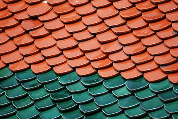 Abstract scene of red Brown and green  earthenware tiles or calls tiles consists of fish scales on the roof of temple bangkok thailand - red and green separate different concept