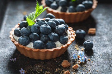 Freshly baked mini tart with blueberries and whipped cream