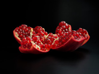 Red ripe cut pomegranate on a dark background