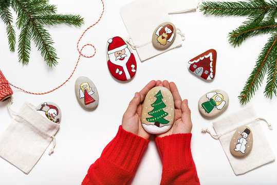 Beautiful hand painted stone with Christmas tree hold by hands. Easy fun kids crafts concept. 
