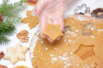 in hand is a gingerbread star. Christmas food. Homemade gingerbread cookies with ingredients for Christmas baking and kitchen utensils on a white table, flour, ginger, chocolate, gingerbread