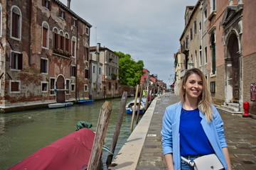 Fototapeta na wymiar Young women in blue shirt next to canal in Venice