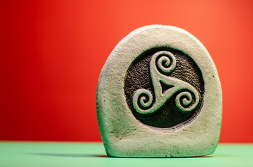 Decorative stone figure with the symbol of a celtic triskele - obrazy, fototapety, plakaty