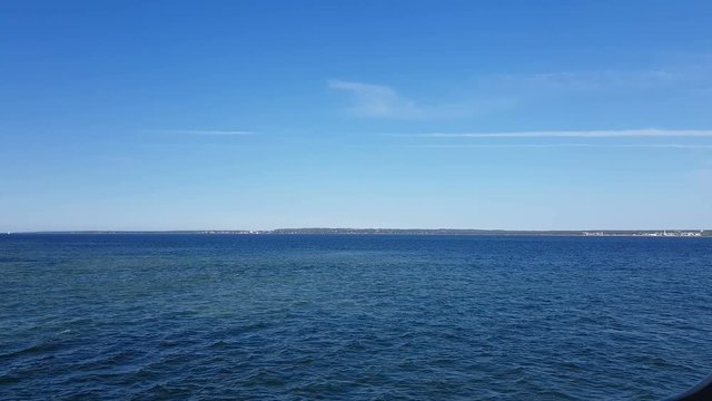 View of the ocean and clouds in the sky. Blue sky with clouds in sunny weather over the ocean. Mountains and ocean on the horizon.