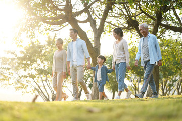 three generation asian family walking in park