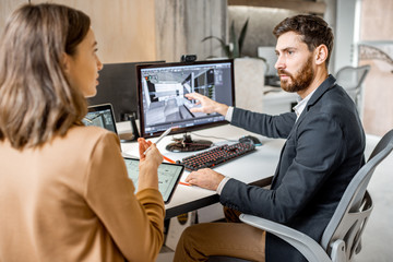 Two creative office employees making interior design on the computer and digital tablet at the modern office of architectural firm. Concept of 3d modeling and digital Interior designing