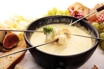 Gourmet Swiss fondue dinner on a winter evening with assorted cheeses on a board alongside a heated...