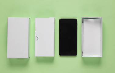 New smartphone with box on green background. Minimalism concept, unboxing. Top view