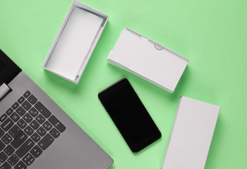 The concept of unboxing, techno blogging. Box with new smartphone, laptop on pastel green...