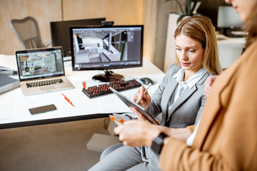 Strictly dressed office employees working with digital tablet and computers at the architectural...