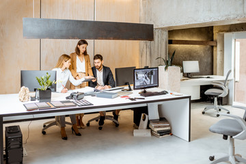 Small group of creative office employees working together on some architectural project in the modern office. Concept of an architectural business and creative work