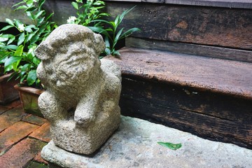 Ancient carved stone lion sits on a doorstep in rural Southeast Asia