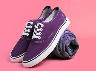 Fashionable sneakers with rolled jeans on pink background. Minimalism fashion concept
