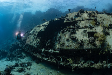 divers visiting an underwater wreck of a metal sailboat on a reef in the Rea Sea, Egypt