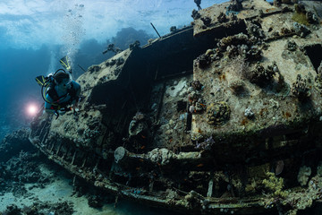 woman diver visiting an underwater wreck of a metal sailboat on a reef in the Rea Sea, Egypt