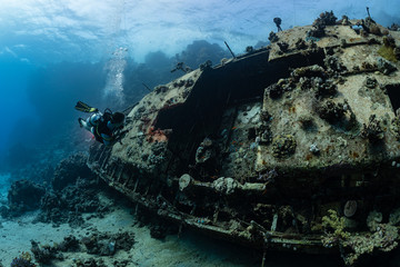 woman diver visiting an underwater wreck of a metal sailboat on a reef in the Rea Sea, Egypt