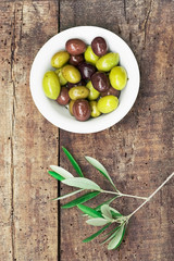 Black and green olives in a small bowl on a rustic wooden background Italian aperitives