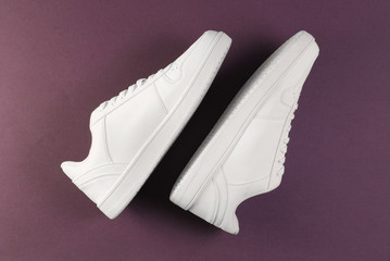 White hipster sneakers on purple background. Top view