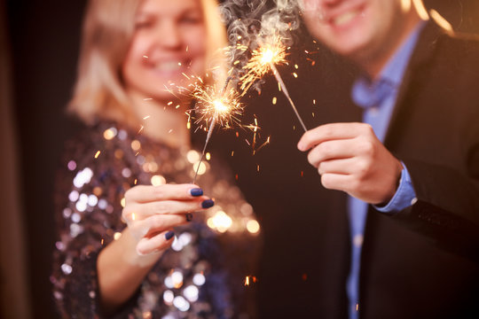 Image of happy couple with sparklers on black background