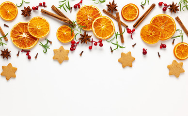  Christmas composition with cookies, dried oranges, cinnamon sticks and herbs on white background....