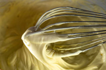 Whisking egg yolks, sugar and "mascarpone" cheese in a bowl to make the traditional, italian "Mascarpone" cream dessert.