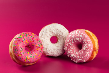 Yummy glazed round donut on a bright pink background