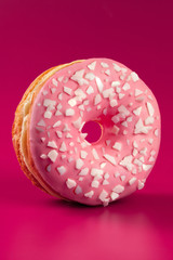 Yummy glazed round donut on a bright pink background