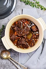 Beef bourguignon in the pot on the grey background, top view