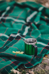 Green cup with hot tea in an autumn forest